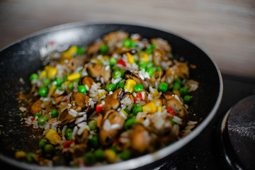 Fried frozen vegetable with rice and see food. Food remains in a black frying pan