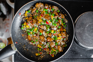 Fried frozen vegetable with rice and see food. Food remains in a black frying pan