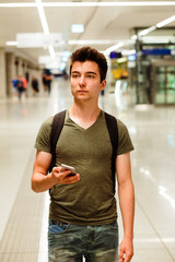 Young man standing in the railway station and planning a travel