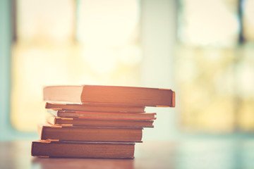 Pile of old books on the table with sunlight and copy space, Stack and one open book, Education learning concept.