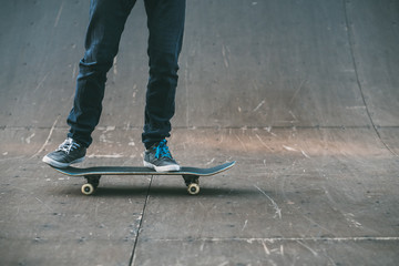 Fototapeta na wymiar Urban skater. Sport hobby and lifestyle. Man on skateboard. Legs in jeans shot. Skate park ramp. Copy space.
