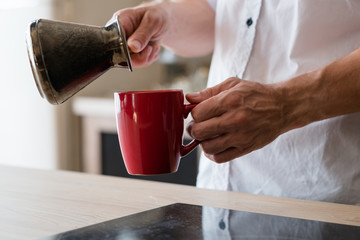 Morning coffee time. New day. Wake up aroma. Man with jezve and red cup.