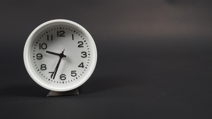 Fototapeta premium White Alarm clock with hour hand and second hand on black background.