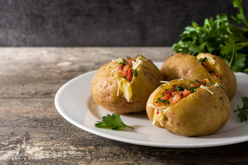 Stuffed potatoes with bacon and cheese on plate on wooden table.