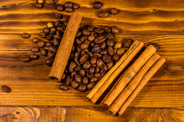 Pile of the coffee beans and cinnamon sticks on wooden table