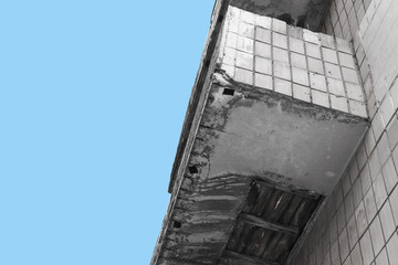 balcony in disrepair on the blue sky background. old gray concrete balconiy with peeling paint and tiles, on the white background with copy space for text, bottom, low angle view.