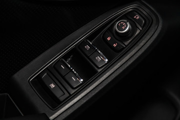 Сlose-up of the car  black interior:  the side door buttons: window adjustment buttons, door lock and other buttons.