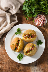 Stuffed potatoes with bacon and cheese on plate on rusty background