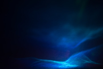 Abstract light waves with glitter effect. Shiny blurry blue lines on dark background. Defocused soft lens flare glow.