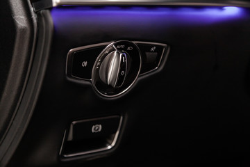 Сlose-up of the car  black interior:  headlight adjustment buttons, parking systems and other buttons .