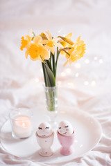Pretty Easter eggs in egg stands with flowers in bed closeup. Celebration.