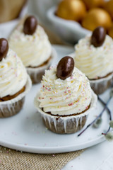 Carrot Easter cupcakr with chocolate egg on top and whipped cream frosting close up seective focus