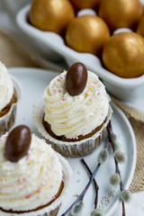 Carrot Easter cupcakr with chocolate egg on top and whipped cream frosting close up seective focus
