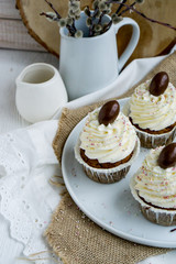 Carrot Easter cupcakr with chocolate egg on top and whipped cream frosting close up seective focus