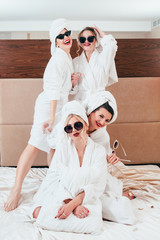 Girls hangout. Leisure joy. Cheerful women posing on bed. Sunglasses, bathrobes and towel turbans...