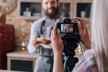 Culinary blog. Food cooking hobby. Couple shooting video tutorial. Man in apron. Woman with camera.