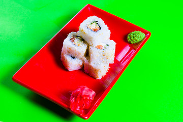 A portion of sushi on a red plate. green background