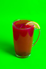 tea with berries decorated with lemon in a mug on a green background