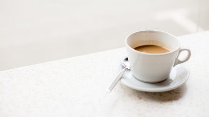 White cup of coffee with milk on light background in the cafe
