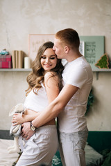 Husband hugs his pregnant wife. Stylish photo in anticipation of a miracle