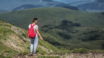 Fototapeta premium man traveler outdoor hike with backpack walks outside ascent in mountains, summer forest. Place for text