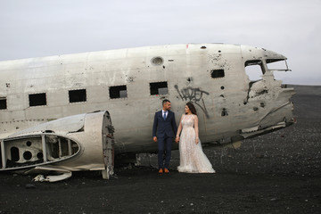 Beautiful wedding couple posing on beach near old plane