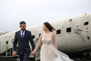 Beautiful wedding couple posing on beach near old plane