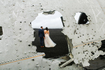 Beautiful wedding couple posing on beach near old plane