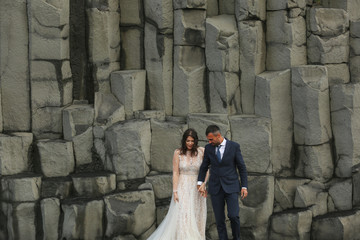 Handsome groom and beautiful bride posing on rocks
