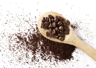 Milled coffee powder with beans and wooden spoon isolated on white background, top view