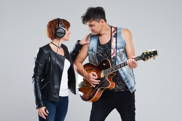Musical artists sing and play electric guitar. Contemporary cover band. Isolated over grey background. Woman and man with headphones sing loudly