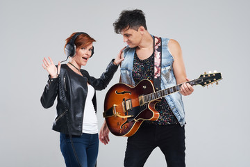 Obraz premium Musical artists sing and play electric guitar. Contemporary cover band. Isolated over grey background. Woman and man with headphones sing loudly
