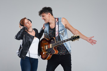 Obraz premium Musical artists sing and play electric guitar. Contemporary cover band. Isolated over grey background. Woman and man with headphones sing loudly