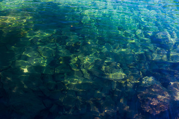 Fototapeta na wymiar Crystal-clear water in the high-mountainous lake of Baduk with stones at the bottom on a summer day.