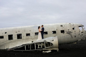 Beautiful wedding couple posing on beach near old plane