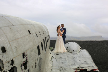 Beautiful wedding couple posing on beach near old plane