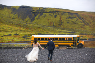 Beautiful wedding couple posing with yellow school bus