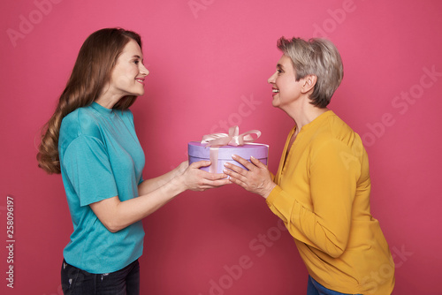 Side view of happy brown-haired girl giving to her mother a present