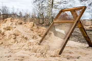Sifting sand through a grid at a construction site. 