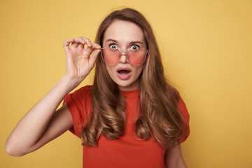 Portrait of surprised brunette young lady in eyeglasses posing in studio