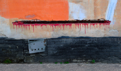 Old wall with graffiti and hole. on the wall Stucco and old bricks. There is a hatch on the wall and the flowing red paint is drawn.
