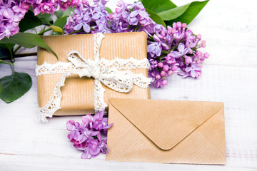 Lilac flowres, gift box and envelope on white wooden background. Retro style. Holiday composition, copy space