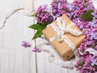 Obraz na płótnie Canvas Lilac flowers, gift box on white wooden background
