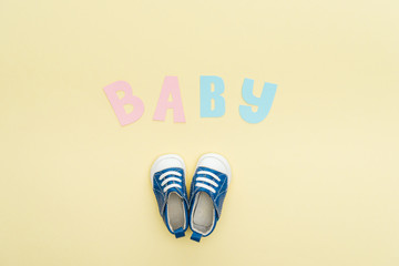 top view of sneakers and baby lettering isolated on yellow