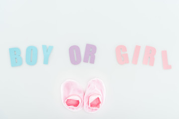 top view of pink booties and boy or girl lettering isolated on white with copy space