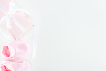top view of pink booties and gift box on white background with copy space