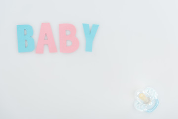 top view of pacifier and pink and blue baby lettering isolated on white with copy space