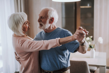 Romantic elder couple dancing in living room