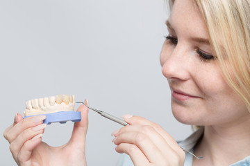 Obraz premium Young female dental technician works on denture in dental laboratory