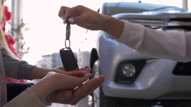 Auto business, family hands of owners new car take keys on background of automobile close-up in sales center